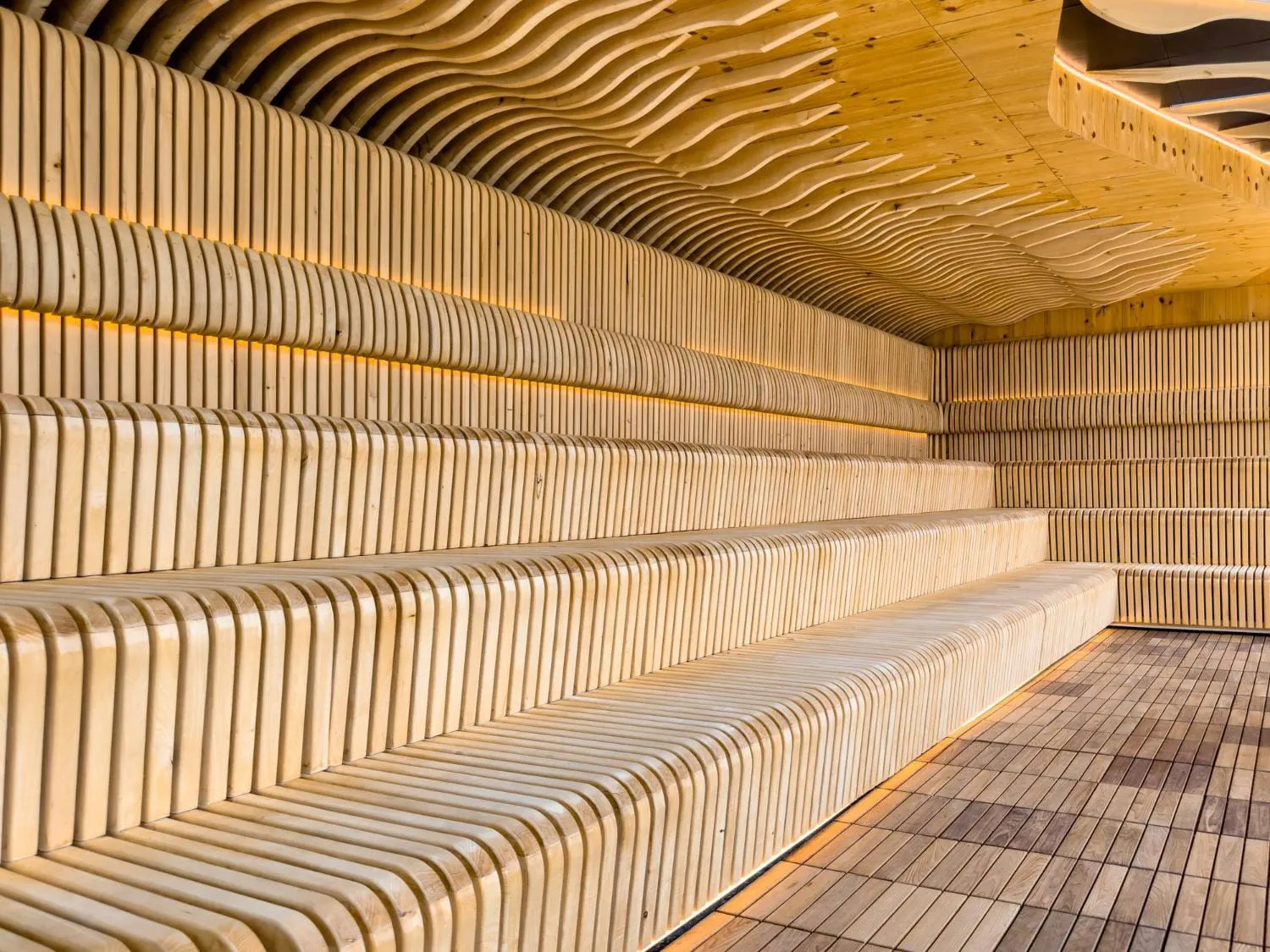 Saunainterieur aus Holz mit übereinander angeordneten Bänken und einer gewellten Decke.