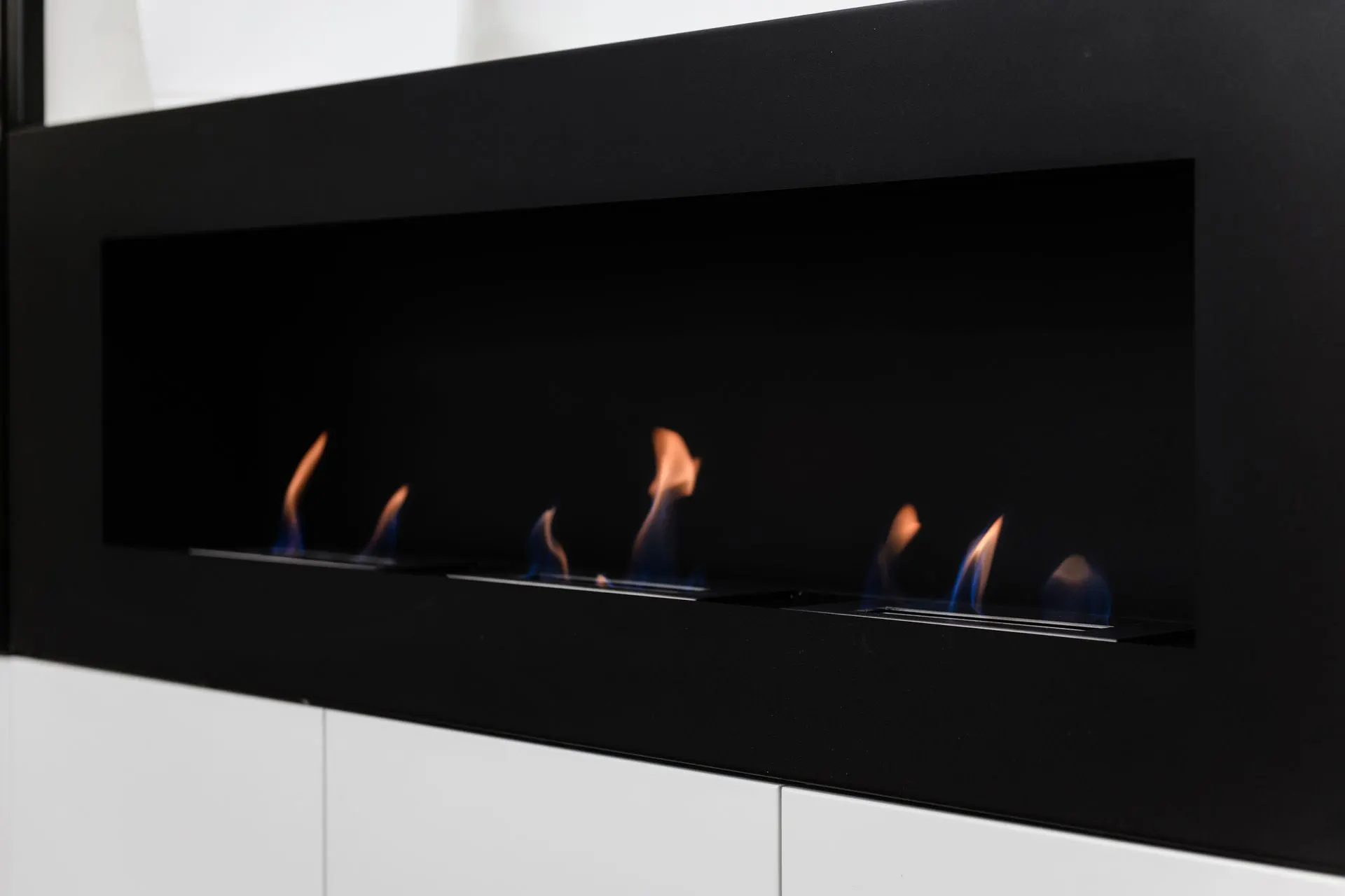 Moderner schwarzer Kamin mit mehreren blauen und orangen Flammen.