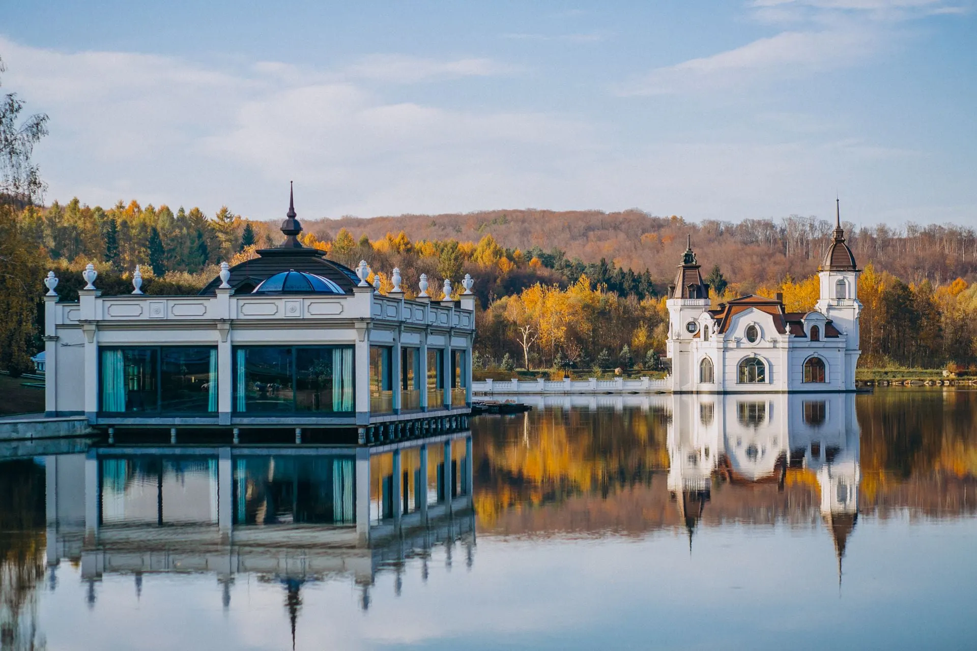 Ein weisses Gebäude spiegelt sich im Wasser eines Sees.
