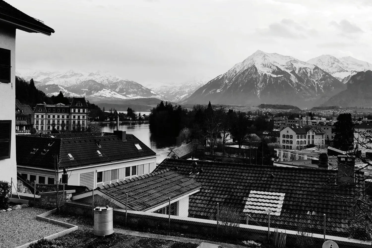 Im Vordergrund ein traditionelles Holzchalet, im Hintergrund ein weisses, historisches Schloss, eingebettet in die Berge.