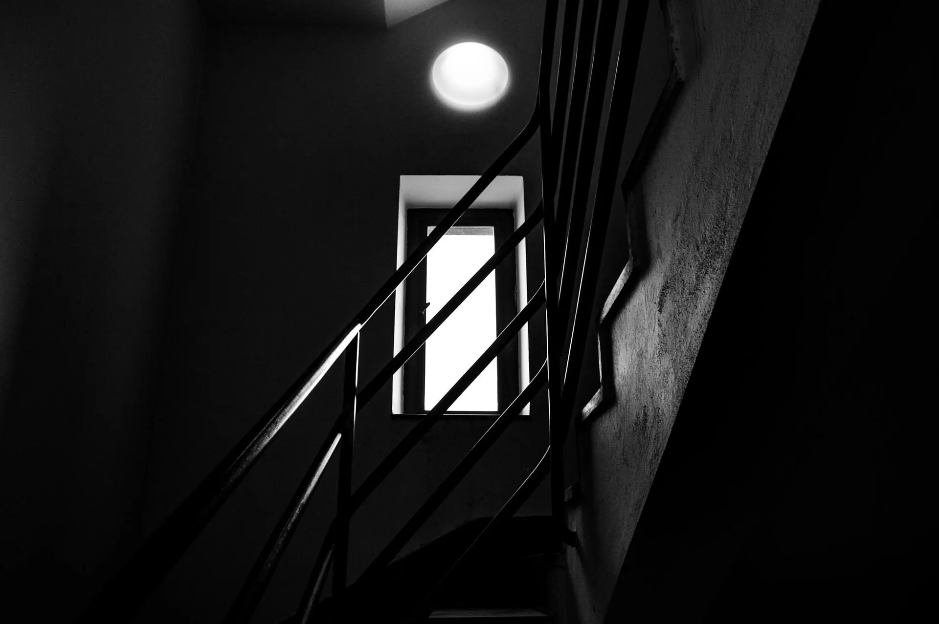 Ein Schwarzweissfoto einer Treppe mit Geländer und Tür.